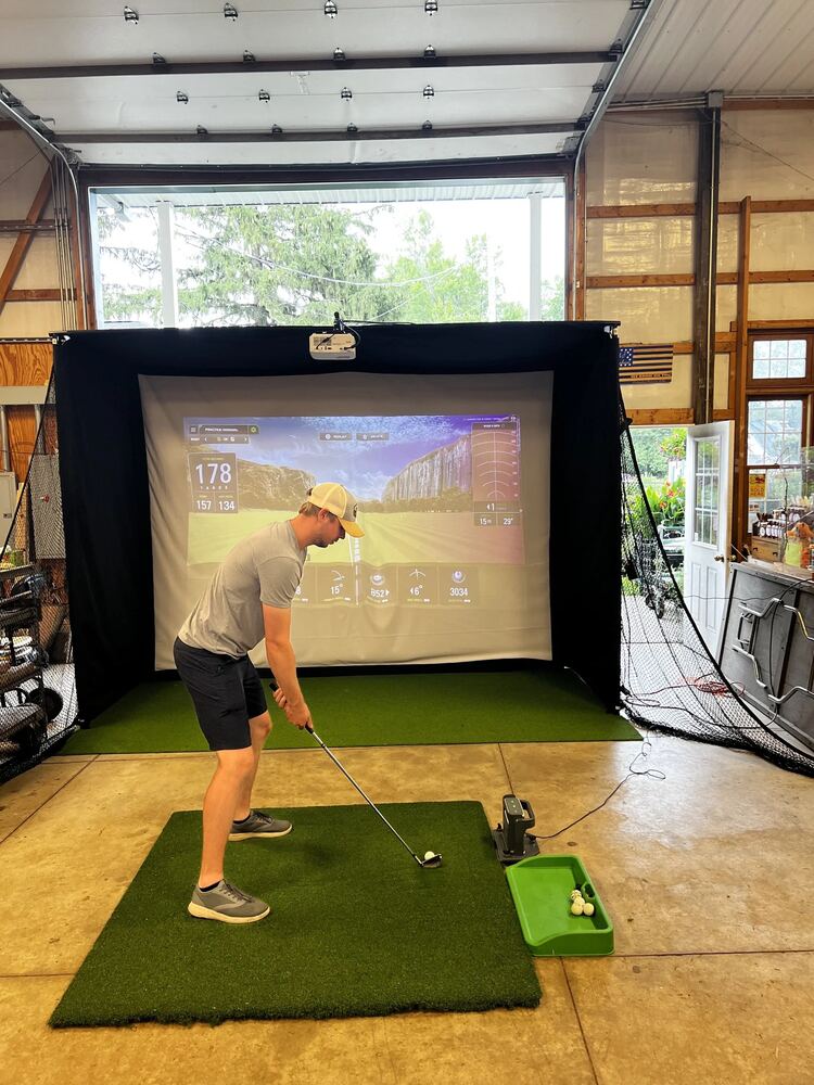 Golfer taking a swing inside a Just Swing Golf Co. indoor simulator setup