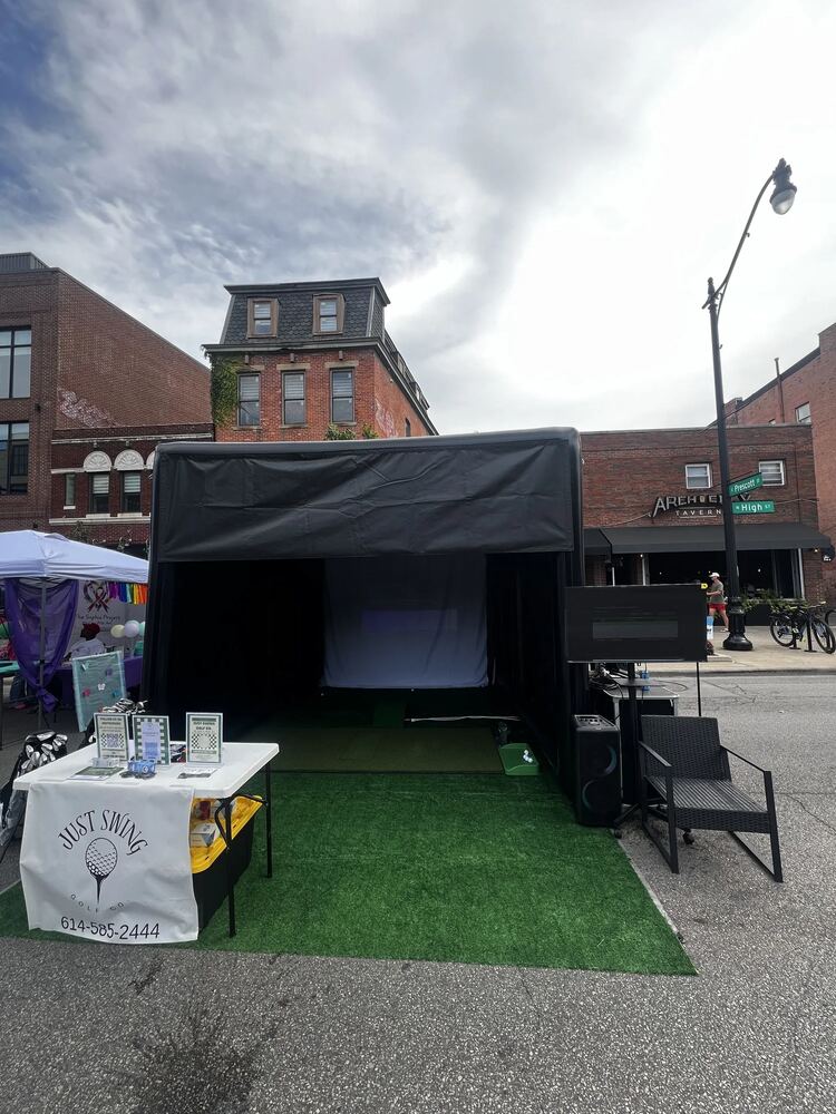 Just Swing Golf Co. simulator set up at a community street festival with branded signage