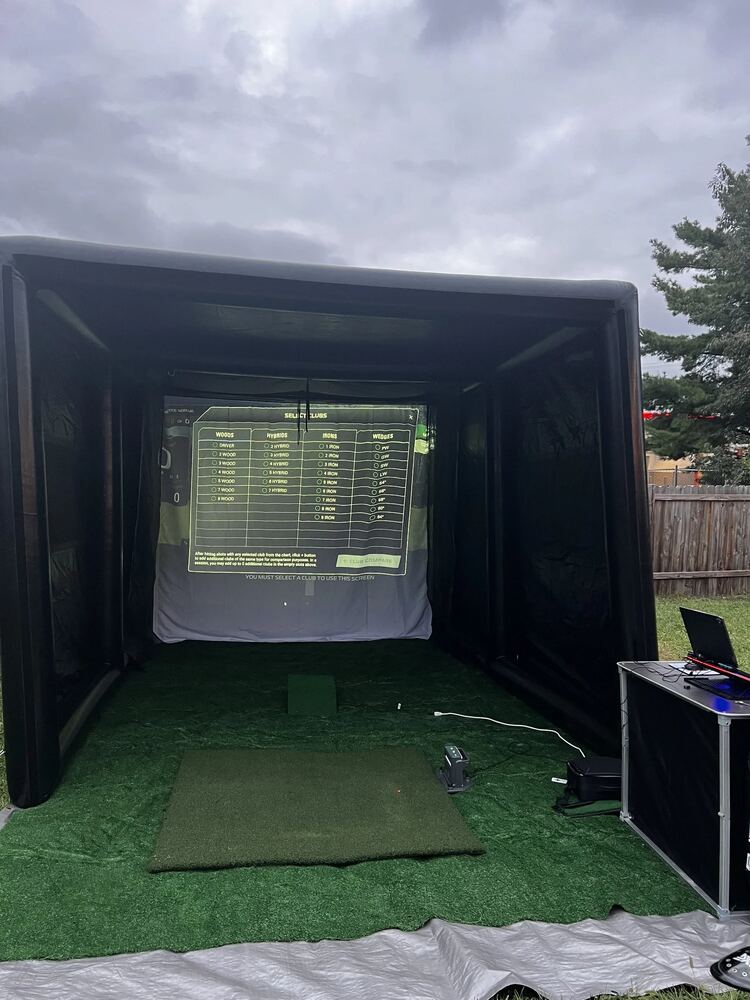 Just Swing Golf Co. outdoor tent simulator setup under a dramatic sky